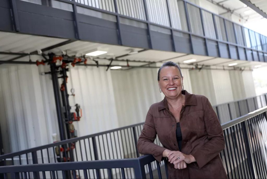 Professional woman smiling proudly leaning against railings in a new construction residential building